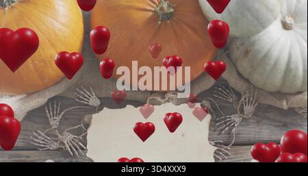 Mostra tre zucche sedute su una bavaglia su tavole di legno con osso di carta garland cuori rossi galleggianti Foto Stock