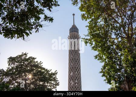 La vista della Torre del Cairo perfora il cielo, incorniciata dal lussureggiante verde vegetale degli alberi circostanti sotto un sole luminoso, Zamalek, il Governatorato del Cairo, Egitto. Foto Stock