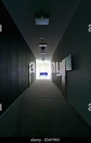Breslavia, Polonia - 20 settembre 2024: Corridoio lungo e buio con porte che conducono alle sale di un grande centro conferenze, illuminato da luce lontana, Foto Stock