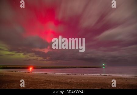 L'aurora boreale (Aurora Boreale) sopra il molo di Berwick e il faro che mostrano sopra le nuvole nelle prime ore del 12 novembre 2025 Foto Stock