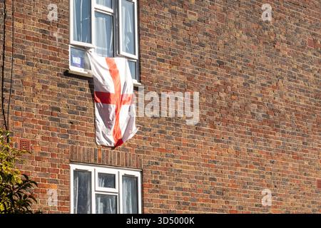LONDRA - 6 OTTOBRE 2025: Bandiera della Croce di San Giorgio appesa da una finestra su una casa di mattoni Foto Stock