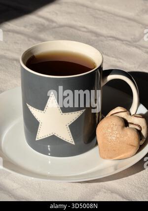 Tazza stellata con tè e biscotti a forma di cuore Foto Stock