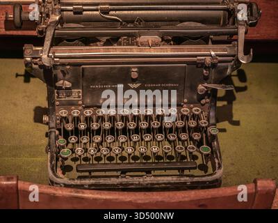 Primo piano ad angolo alto di una tastiera nera vintage Wanderer-Werke su una scrivania in feltro verde. Foto Stock