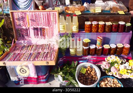 Uno shot colorato e ravvicinato di vari vasetti di conserve fatte in casa, tra cui pasta di peperoni rossi, marmellate e verdure sottaceto, visualizzati in rosa e bianco Foto Stock