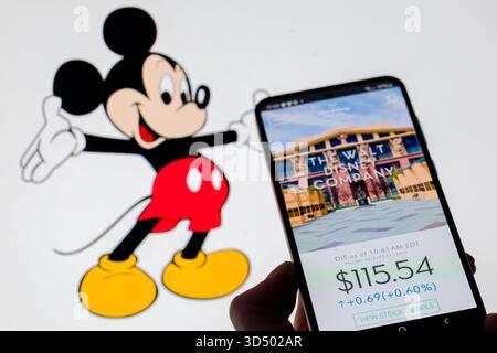 Bruxelles, Belgio. 12 novembre 2025. La Walt Disney Company è esposta su un telefono cellulare con il Walt Disney Topolino visibile sullo sfondo, in questa illustrazione fotografica a Bruxelles, Belgio, il 12 novembre 2025. (Foto illustrazione di Jonathan RAA/NurPhoto) crediti: NurPhoto SRL/Alamy Live News Foto Stock