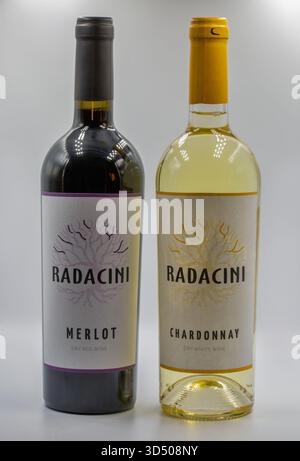 Kiev, Ucraina - 16 agosto 2024: Due bottiglie di vino Radacini affiancate: Rosso secco Merlot e bianco secco Chardonnay. Disegno del logo della radice ad albero sui minimi Foto Stock