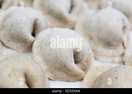 Gli gnocchi riposano su una superficie piana in un'accogliente cucina spolverata di farina. Sono pronti per essere cucinati, mostrando le loro forme e consistenze uniche. Foto Stock