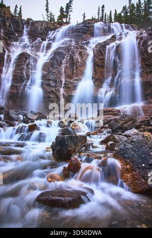 Cascata Tangle Falls che scorre sul paesaggio roccioso con la lussureggiante foresta di Jasper Foto Stock