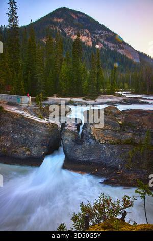 Ponte naturale che scorre lungo il fiume e il paesaggio montano nella lussureggiante foresta Foto Stock