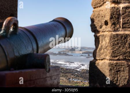 Un cannone sulle mura della città di Essaouira, che indica l'oceano Atlantico Foto Stock