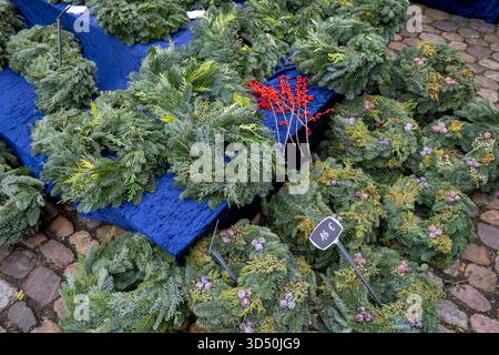 Bellissime ghirlande natalizie o ghirlande fatte a mano con rami di pino per la decorazione, esposte in un mercato di strada in inverno Foto Stock