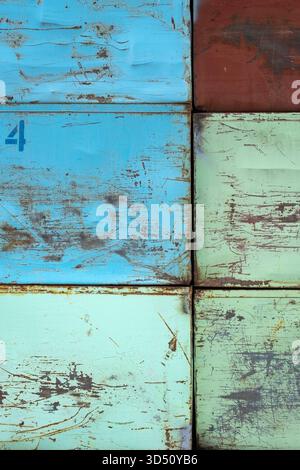 Vista geometrica astratta di scatole in acciaio arrugginite e graffiate per l'agricoltura in tonalità blu e verde in una griglia Foto Stock