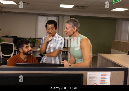 Diversi colleghi che analizzano il grafico a barre stampato in un moderno ufficio open space, con impianto in vaso Foto Stock