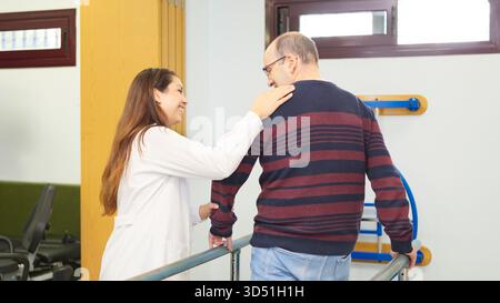 Donna che assiste l'uomo anziano durante la sessione di terapia fisica Foto Stock