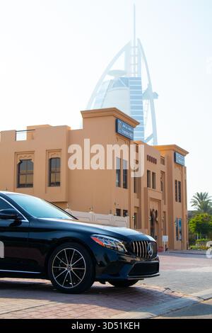 Dubai, Emirati Arabi Uniti - 13 luglio 2024: Vista ravvicinata del quartiere anteriore e del cofano di una Mercedes-Benz nera Classe C parcheggiata vicino a uno spot commerciale in stile tradizionale Foto Stock