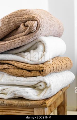Primo piano di maglioni caldi in maglia in tonalità pastello e beige, ben impilati. Foto Stock