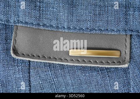 Pelle vuota e patch bag dorata cucita su sfondo in tessuto blu Foto Stock