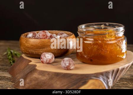 marmellata d'arancia a base di arance e frutta, essiccata in sciroppo di zucchero, frutta kumquat intera in polvere bianca, un vaso di vetro con marmellata d'arancia dolce è sul ta Foto Stock