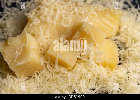 formaggio duro giallo grattugiato su una grattugia per pizza o pasta, formaggio grattugiato giallo con pezzi per cucinare vari alimenti Foto Stock