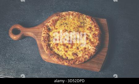 Pizza al formaggio appena sfornata guarnita con erbe aromatiche e presentata su un rustico tavolo di legno Foto Stock
