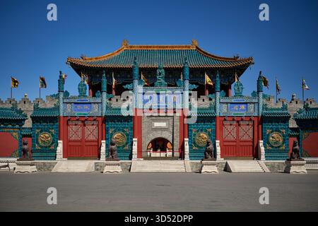 Facciata tradizionale del palazzo del tempio cinese con piastrelle turchesi vetrate, tetto ornamentale dorato, porte cerimoniali rosse, facciata simmetrica, esterno diurno Foto Stock
