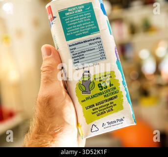 Parigi, Francia - 10 settembre 2025: Mano che tiene in mano un cartone per bevande Tetra Pak con testo in tedesco che mette in evidenza il 93% di materiale vegetale che mostra nutrizione fa Foto Stock