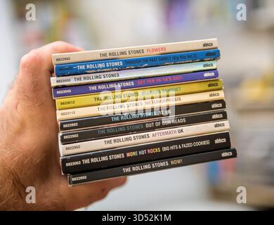 Parigi, Francia - 9 settembre 2025: Mano che tiene in mano una pila di rari album dei Rolling Stones ABKCO SACD Super audio CD, tra cui Flowers, Beggars Banquet, e. Foto Stock