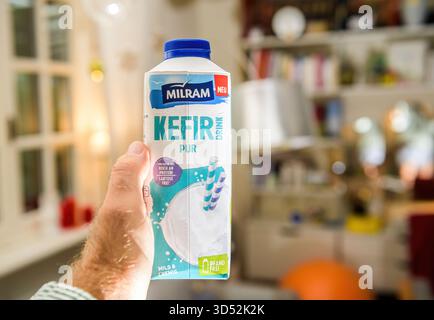 Parigi, Francia - 10 settembre 2025: Una persona tiene in mano un cartone di bevanda Milram kefir pur con un tappo blu e un'etichetta, con testo tedesco e marchio, contro Foto Stock