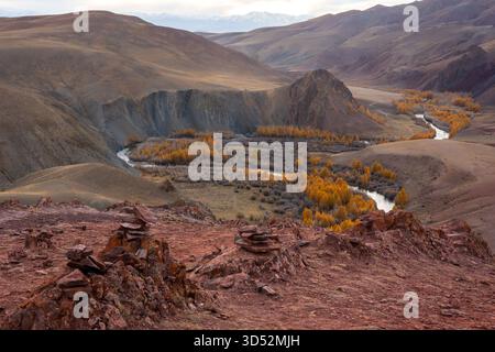 Maestosa valle con fiume che si piega tra alberi autunnali circondati da aride colline e orizzonte Foto Stock