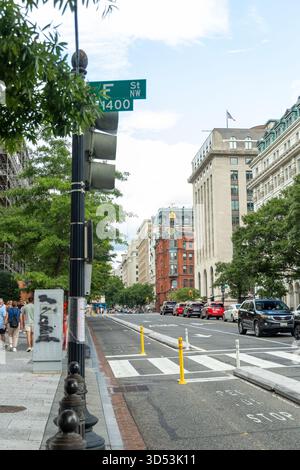Una strada con un passaggio pedonale e un cartello verde. Ci sono molte auto per strada, inclusa una rossa. Washington, DC Foto Stock