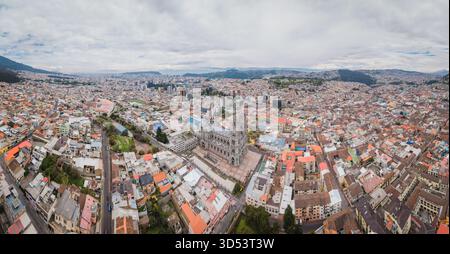 Vista panoramica aerea della grande Basilica del voto Nacional sorge maestosamente in mezzo a un vasto paesaggio urbano sotto un vasto cielo nuvoloso, Quito, Ecuado Foto Stock