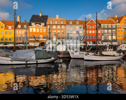 Copenaghen, Danimarca - 8 novembre 2025: Vista serale delle barche e dei colorati edifici storici lungo il lungomare di Nyhavn. Foto Stock