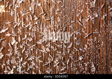 Parete in legno coperta da fiocchi di neve. Sfondo invernale. La tavola rustica marrone crea un caldo stile rustico. Materiale di finitura naturale. Dettagli Foto Stock