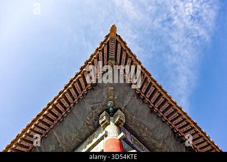 Vista verso l'alto di un angolo decorato sul tetto nella città Proibita contro un cielo luminoso Foto Stock