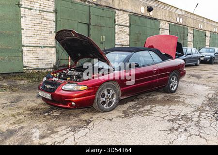 Una capote rossa con cofano aperto in un garage con porte multiple Foto Stock