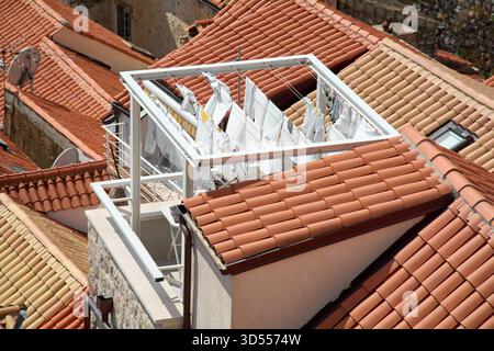 Un'autentica vista della vita locale nella città vecchia di Dubrovniks. La lavanderia si asciuga su una griglia metallica sopra gli storici tetti in terracotta, mostrando un viaggio autentico Foto Stock