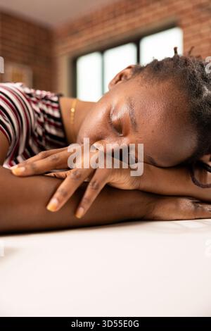 Primo piano di una donna che si riposa sulla scrivania con gli occhi chiusi, facendo un breve pisolino durante l'orario di lavoro. Stanco imprenditore in un ufficio domestico dorme tranquillamente dopo aver completato attività impegnative. Foto Stock