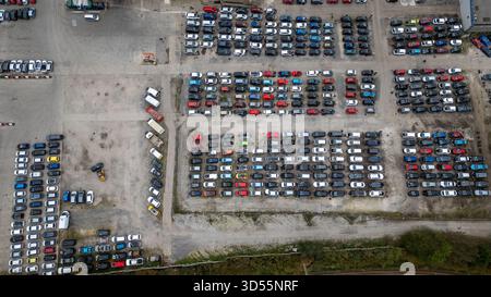 Vista aerea di un grande parcheggio all'aperto pieno di numerosi veicoli parcheggiati in file ordinate, con alcuni camion e un carrello elevatore visibile a U-pull-it York, Foto Stock