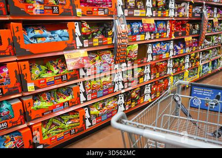 Prospettiva di un acquirente con un carrello vuoto che guarda lungo il corridoio stagionale con sacchetti di caramelle di Halloween sugli scaffali all'interno di un negozio di Smith's Foto Stock