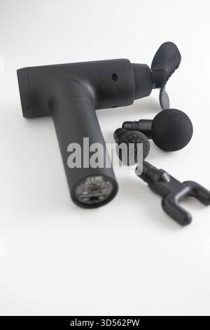 pistola per massaggio nera per articolazioni e muscoli con vari strumenti per massaggi su sfondo bianco Foto Stock