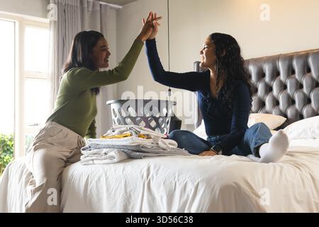 Ampia scelta di amiche, lavanderia pieghevole sul letto in camera da letto, con cestino in plastica Foto Stock