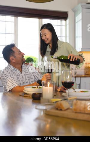 Condividete vino e conversazione, coppia asiatica che cenano insieme a casa Foto Stock