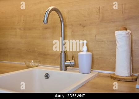 Cucina moderna e pulita, lavandino elegante con finiture eleganti, zona pranzo moderna con illuminazione soffusa, elegante cucina che mette in risalto l'igiene e. Foto Stock