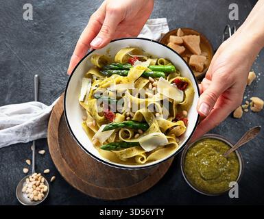 Fituccine con pesto di basilico e pinoli su un piatto bianco. Fituccine al pesto secondo una tradizionale ricetta italiana su un backgroun scuro Foto Stock