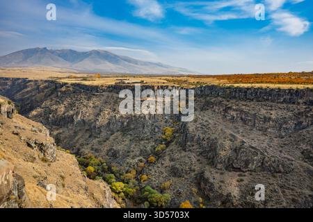 Una catena montuosa con un fiume che la attraversa. Le montagne sono ricoperte di alberi e il fiume è marrone Foto Stock