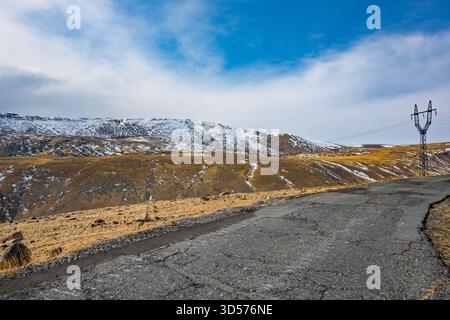 Una strada con una linea elettrica che la percorre. Il cielo è blu e la strada è vuota Foto Stock