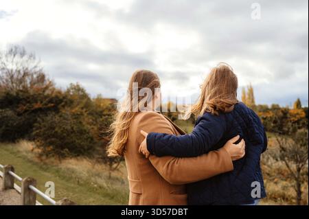 Madre e figlia che guardano in lontananza il paesaggio autunnale. Foto Stock