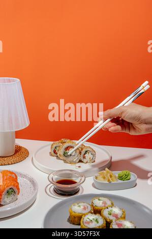 set di sushi con bacchette in mano su uno sfondo luminoso Foto Stock