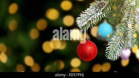 Ramo dell'albero di Natale con ornamenti su luci sfocate su sfondo scuro, effetto bokeh. Design banner Foto Stock