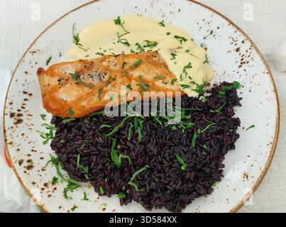 Pesce di merluzzo bulgaro con riso nero e salsa bearnaise Foto Stock